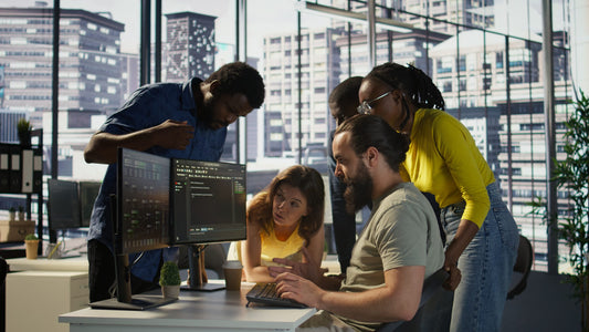 A development team gathered around a monitor reviewing code together